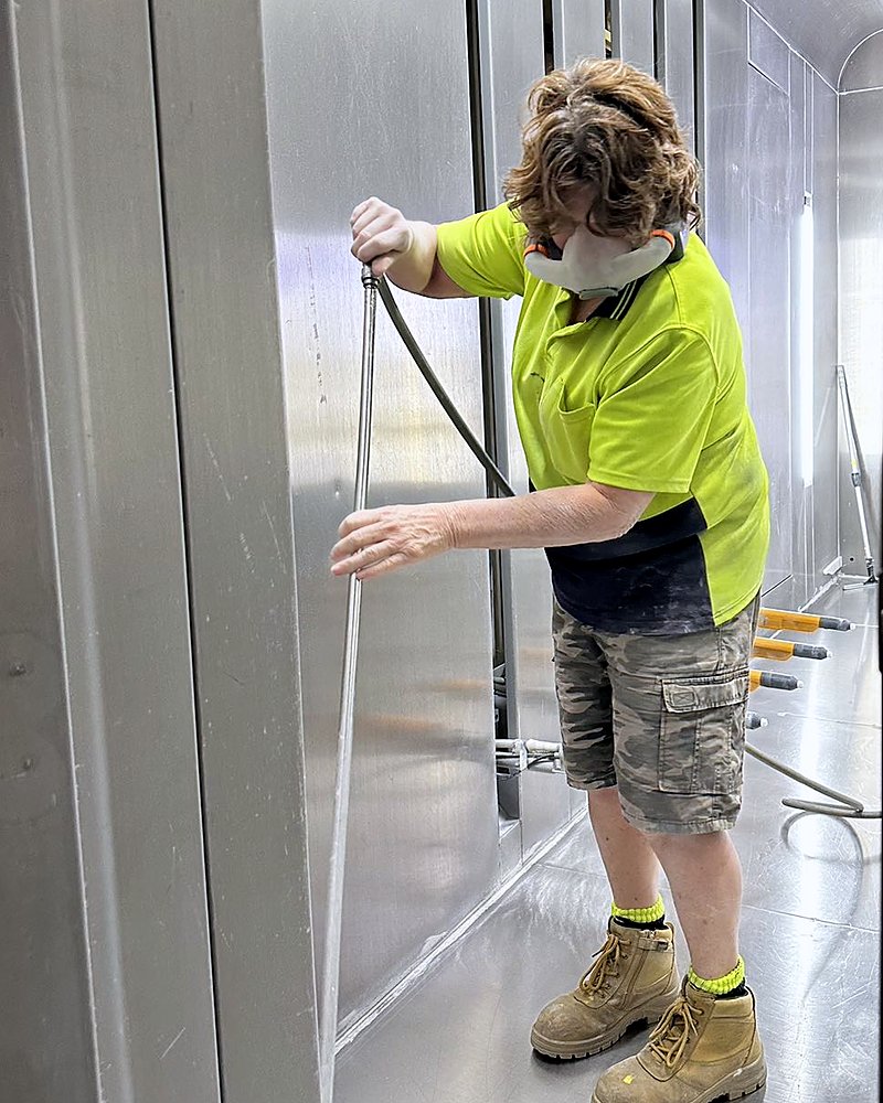 Almax Aluminium worker cleaning a spray booth while wearing an AYO WX half-face powered respirator